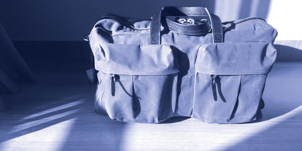 blue-tinted photo of a large bag sitting on a wooden floor